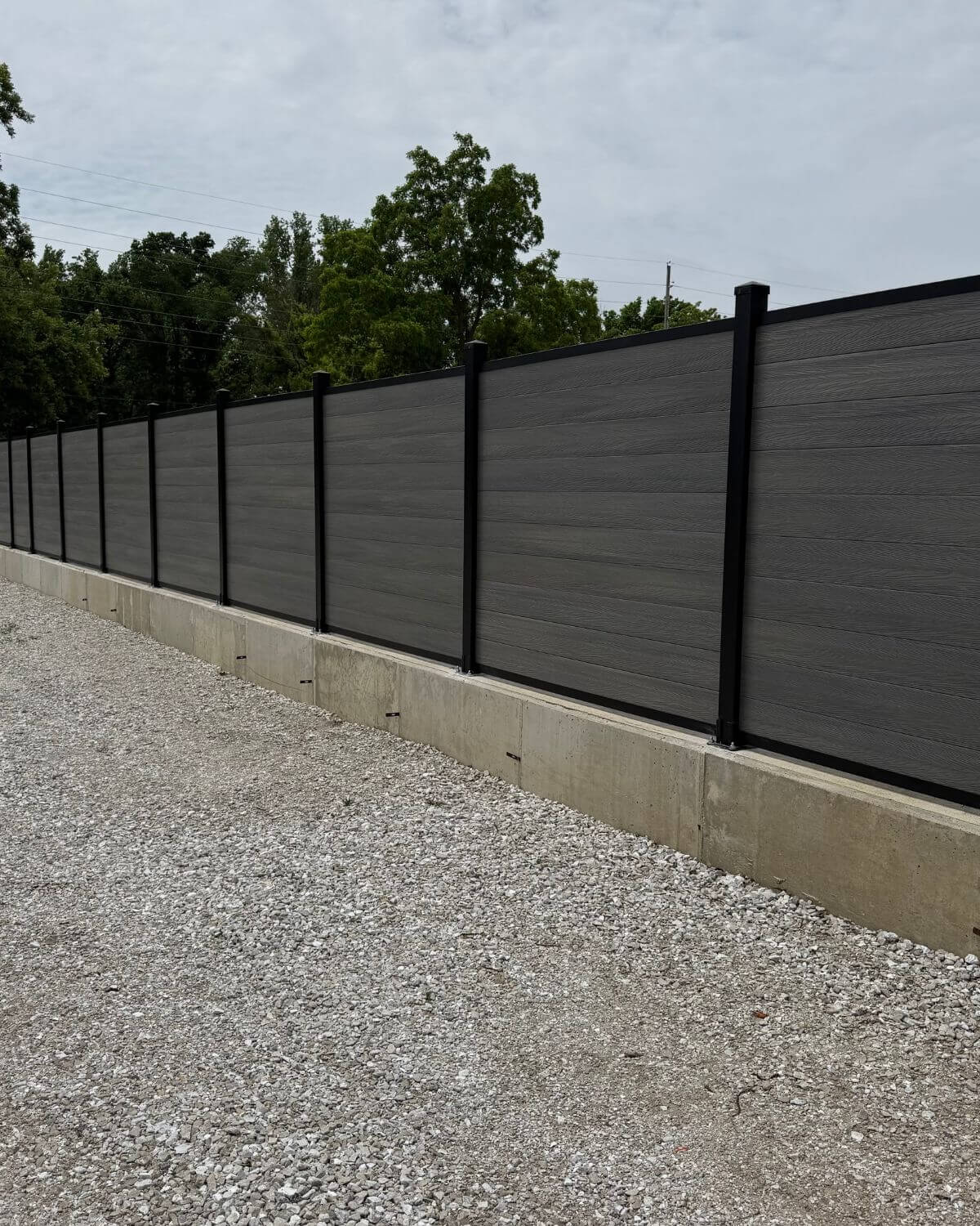 An installed storm grey composite fence, mounted on concrete