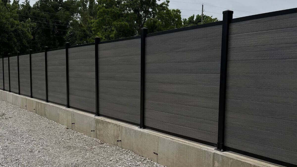 An installed storm grey composite fence, mounted on concrete